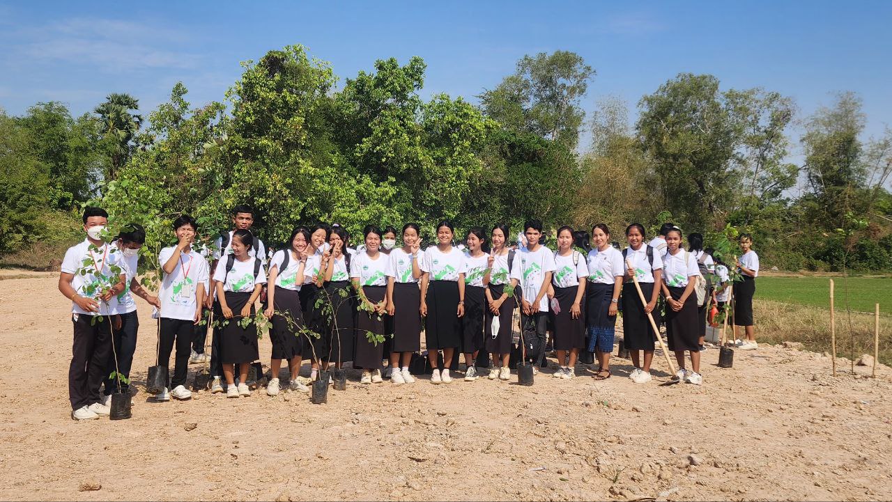 Group of students smiling at the camera standing next to pots of plants