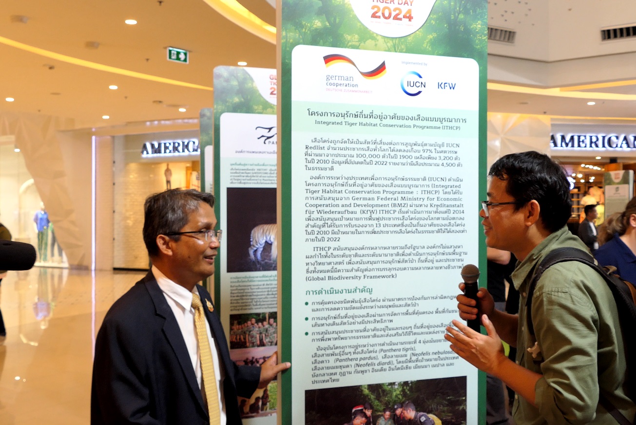 Two people standing and talking to each other in front of exhibition board