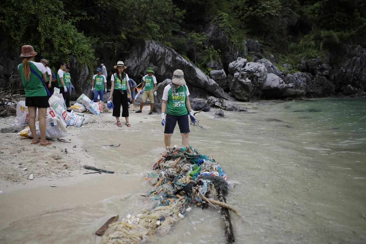 A volunteer was shocking in front of huge pile of waste on the beach of Vung Ha islet, Ha Long Bay