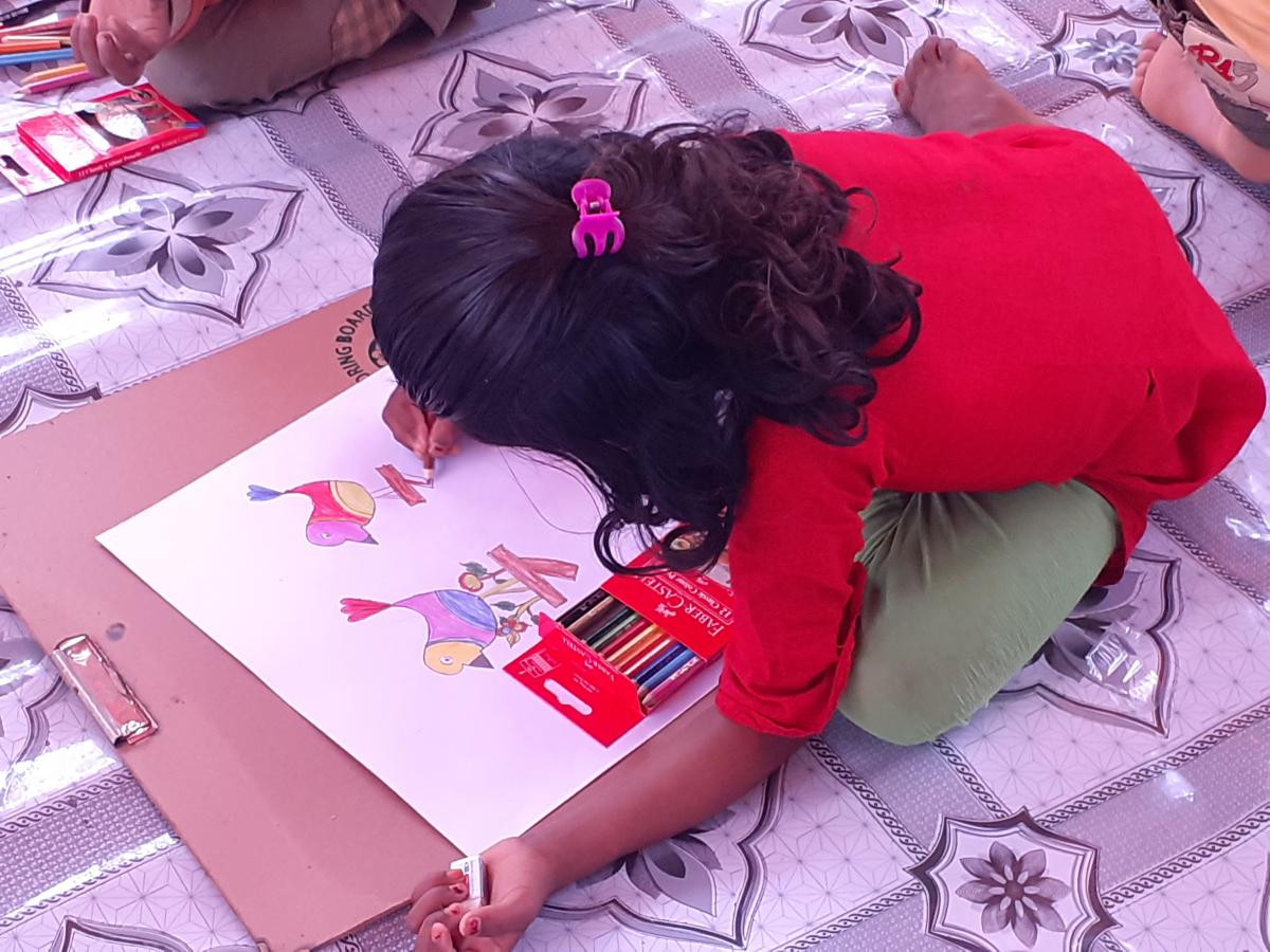 A school child is busy with her drawing with full concentration