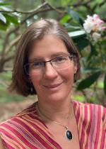 woman with glasses and striped shirt in front of tree