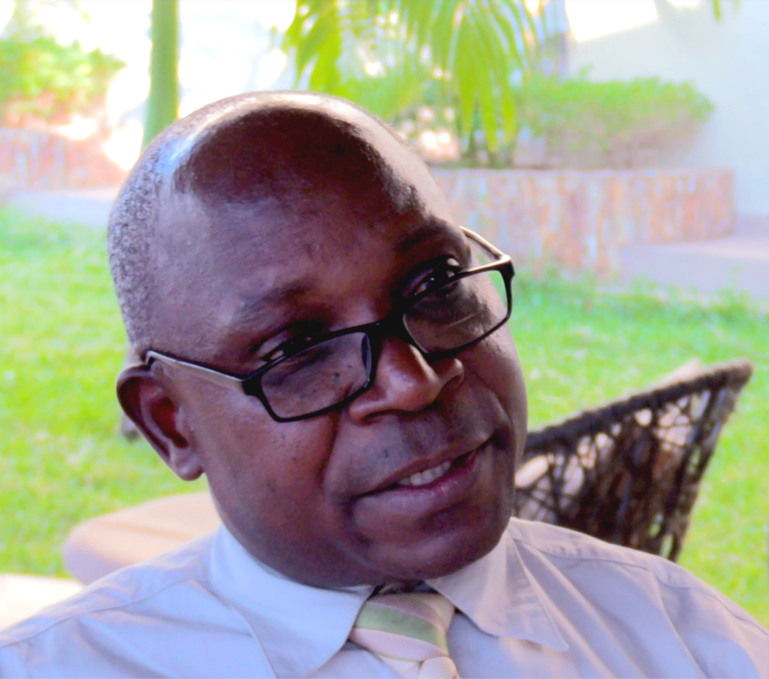 Bald man in glasses and tie talking to camera
