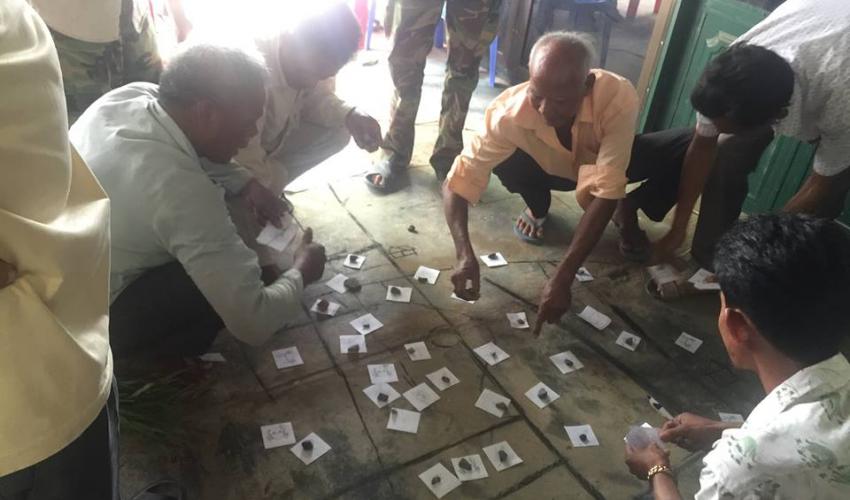 A group of men use different numbers of slips of paper to show which resources they value most