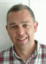 close up of man smiling - plaid shirt - short grey hair
