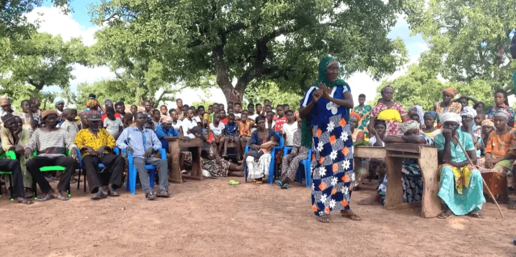 A member of the Women's Organic Shea Nut Cooperative addressing fellow community members in the Wechiau Community Hippo Sanctuary in Ghana.