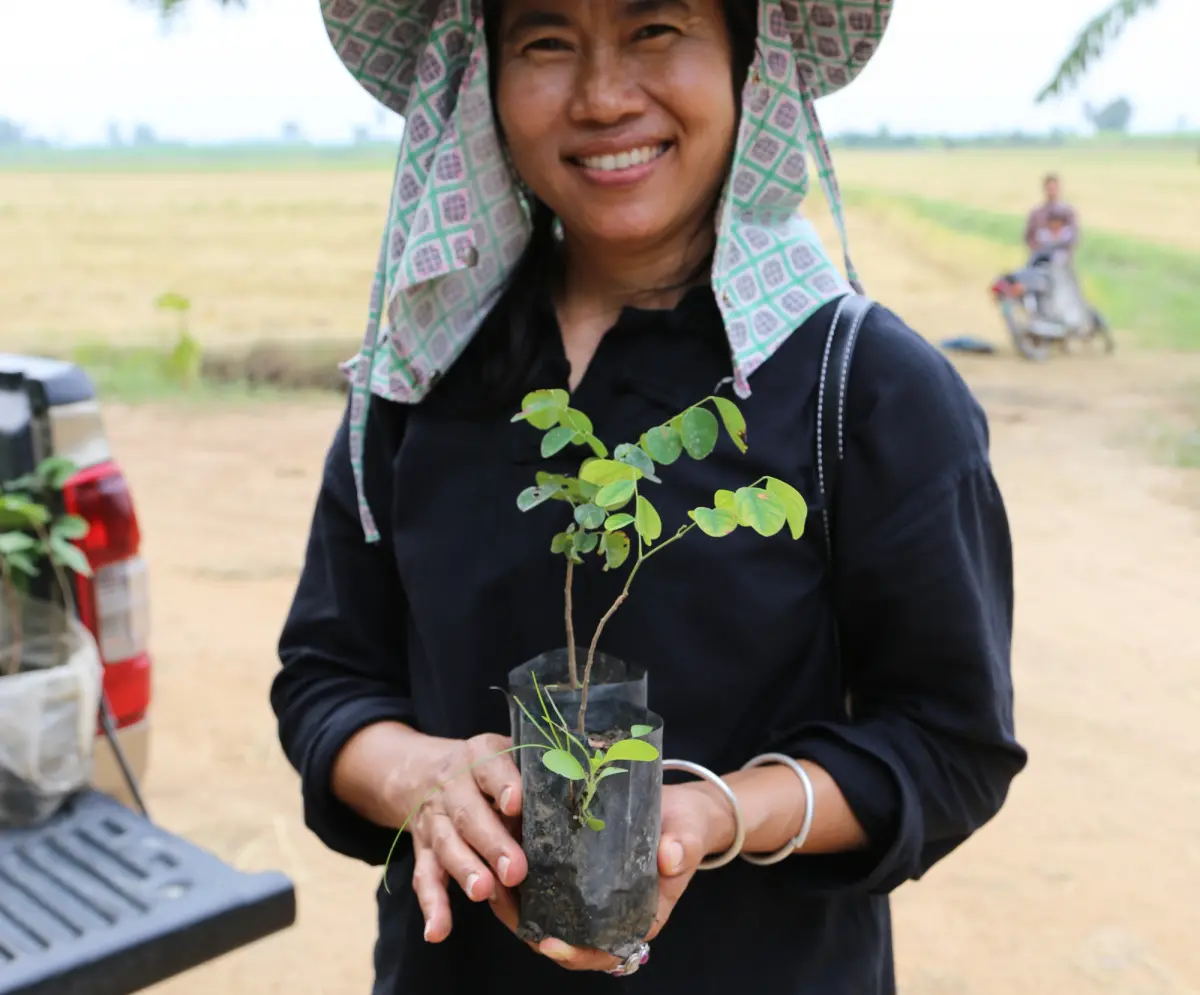 woman smiling and holding seedling