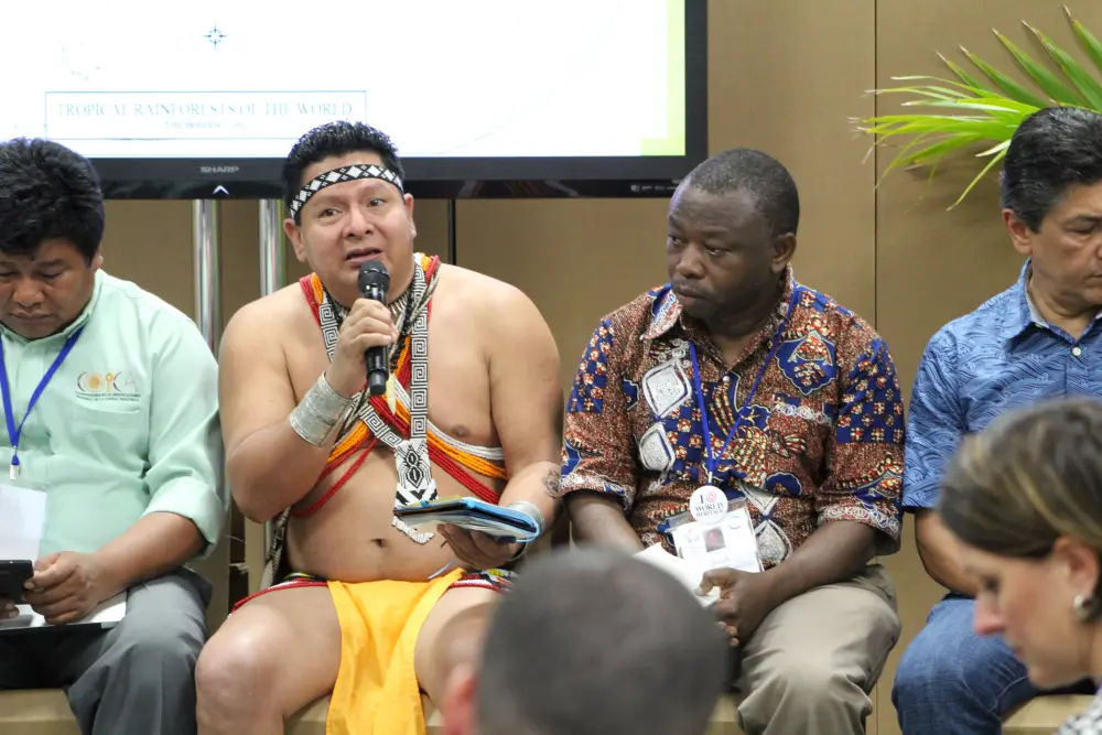 Man in indigenous outfit talks on stage
