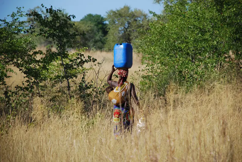 Een vrouw in Mozambique brengt water van de bron naar haar dorp.